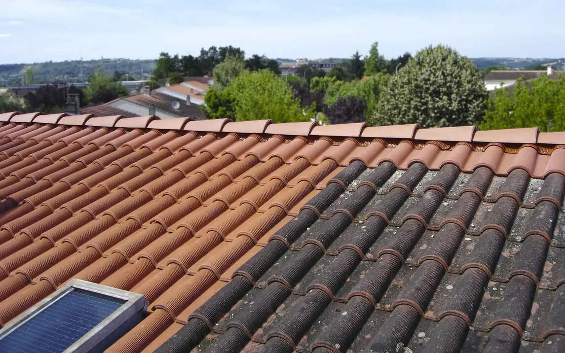 Vu sur une toiture à moitié nettoyée avec à gauche, des tuiles propres et nettoyer et à droite des tuiles sales qui n'ont pas encore été nettoyées. Un exemple de nettoyage en cours par neves et fils dans l'Essonne.